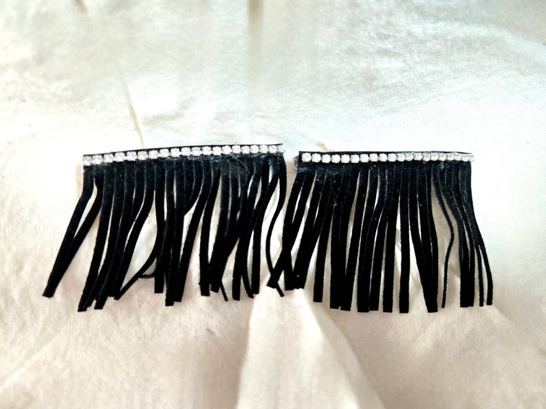 May include: Two black fringe trims with a row of clear rhinestones at the top.