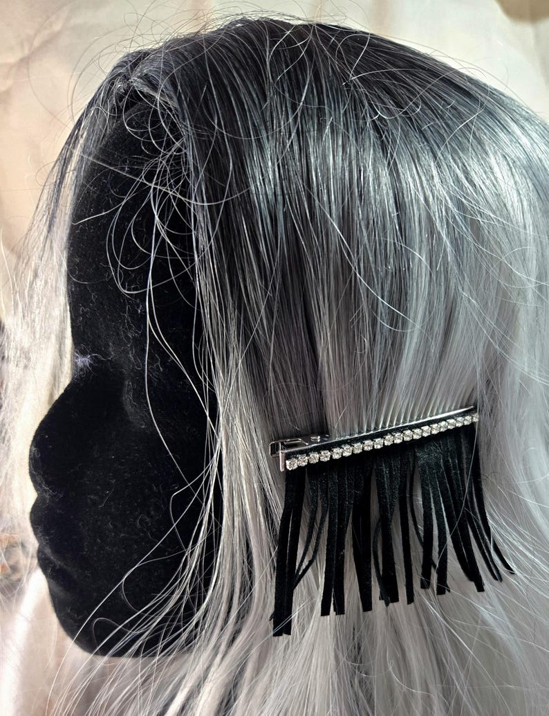 May include: A black hair clip with a row of rhinestones and a fringe of black tassels. The clip is in a silver tone.