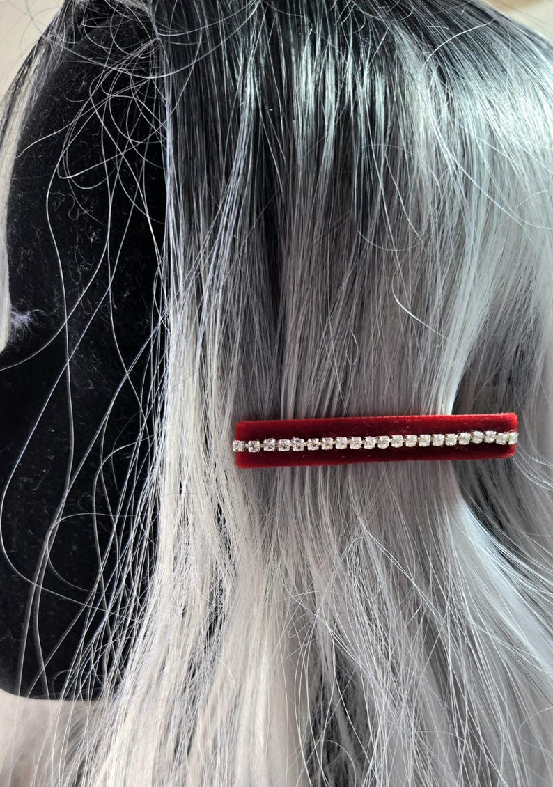 May include: A red velvet hair clip with a row of clear rhinestones.