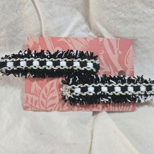 May include: Two black and white checkered ribbon hair clips with frayed edges.