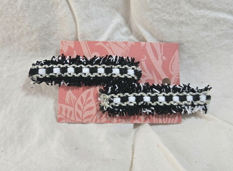 May include: Two black and white checkered ribbon hair clips with frayed edges.