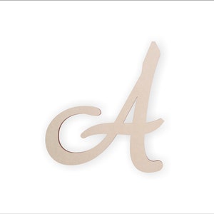 Puede incluir: Una letra "A" de madera en fuente cursiva. La letra es de color beige claro con un acabado liso y una ligera sombra, sobre un fondo blanco. El diseño es simple y elegante, adecuado para la decoración del hogar o proyectos de manualidades.