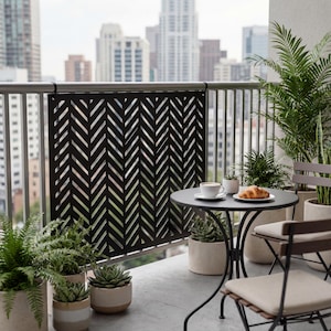 Könnte beinhalten: Balkonszene mit einem schwarzen Metallgitter mit Fischgrätmuster. Ein kleiner runder Tisch mit einer Tasse Kaffee und einem Croissant steht neben einem Stuhl. Topfpflanzen und Stadtgebäude sind im Hintergrund.