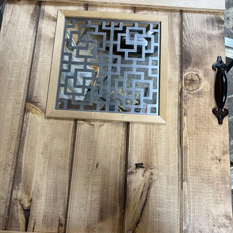 Puede incluir: Puerta de madera con una rejilla decorativa de metal y un tirador negro. La puerta est&aacute; hecha de tablones de madera verticales con un acabado natural. La rejilla met&aacute;lica es cuadrada y tiene un patr&oacute;n geom&eacute;trico. El tirador es ornamentado.
