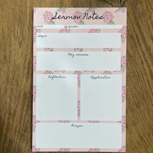 May include: A pink Sermon Notes notepad with floral accents. The notepad features sections for date, speaker, topic, key verses, reflection, application, and prayer. The words "Sermon Notes" are written in cursive at the top.