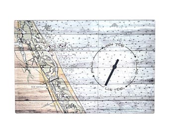 Puede incluir: Un reloj de pared rectangular con una carta náutica de la costa de Florida impresa sobre un fondo de tablones de madera. La esfera muestra un indicador de marea circular con el texto High Tide, Falling, Low Tide y Rising alrededor de una manecilla negra.
