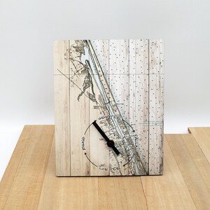 May include: A wooden clock with a nautical map design featuring a tide chart. The clock face shows "High Tide", "Low Tide", "Rising", and "Falling".
