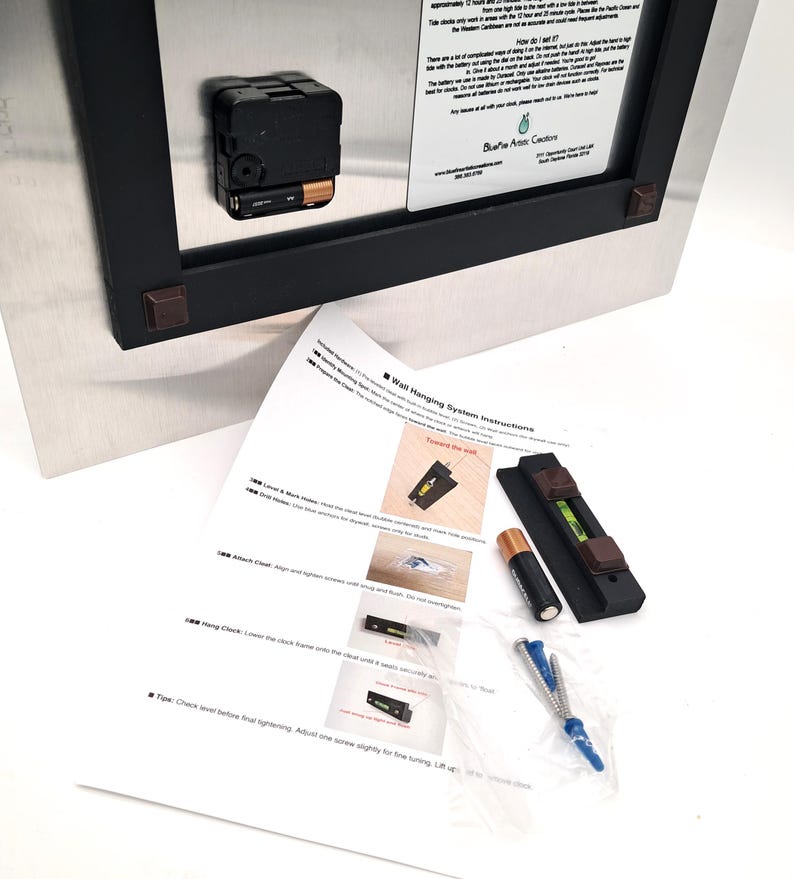 May include: The back of a rectangular metal clock with a black battery-operated mechanism and a white information label. Included are wall hanging instructions, a black level tool, a single AA battery, and a plastic bag with screws and anchors.