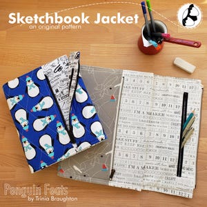 May include: A blue sketchbook jacket with a penguin pattern, a gray sketchbook jacket, and an open sketchbook with pens and pencils. The text "Sketchbook Jacket" and "Penguin Feats" are visible.