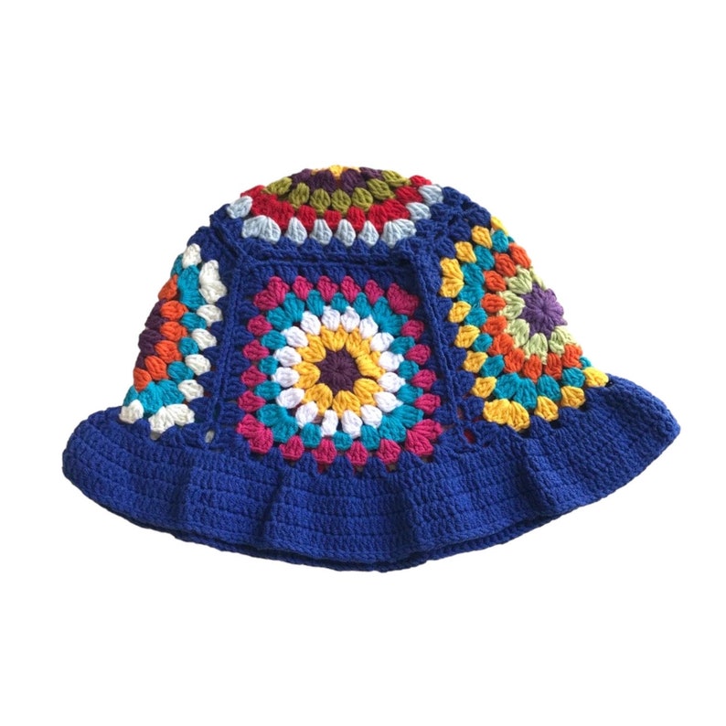 May include: A handmade crochet bucket hat in a vibrant patchwork design. The hat features a deep blue brim and is adorned with colorful squares in shades of yellow, pink, orange, green, and white. This unique hat is perfect for adding a touch of bohemian flair.