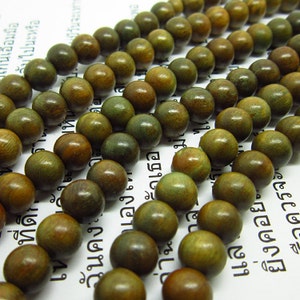 May include: A strand of round, wooden beads with a green and brown mottled colour. The beads are strung together on a clear thread.