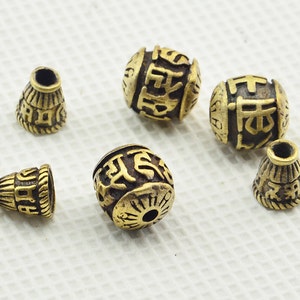 May include: Six gold-coloured metal beads with intricate designs and Chinese characters. The beads are round and have a slightly textured surface.