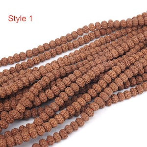 Può includere: Primo piano di una collana di perline marroni, probabilmente realizzate con materiali naturali. Le perline sono piccole e rotonde, con una texture leggermente ruvida. La collana è lunga e sembra essere composta da più fili di perline intrecciati insieme. Il testo "Style 1" è visibile nell'angolo in alto a sinistra dell'immagine.