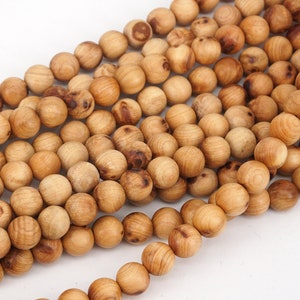 May include: A strand of natural wood beads, each bead is round and has a light brown colour. The beads are arranged in a pile, showing the texture of the wood.