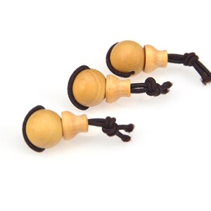 May include: Three wooden beads with brown string attached. The beads are round and have a small wooden stem attached to the string.