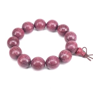 May include: A purple wooden beaded bracelet with a tassel. The beads are round and have a smooth, polished finish.