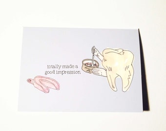 May include: A light blue greeting card with a dental theme. The card features a cartoon tooth holding a bowl with a spoon, a pink dental impression tray, and the text "totally made a good impression."
