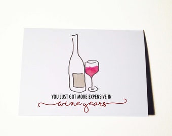 May include: A white card with a hand-drawn illustration of a wine bottle and glass. The text reads "You just got more expensive in wine years."