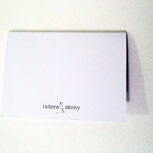 May include: A white card with the text "ratbone skinny" printed in black ink.