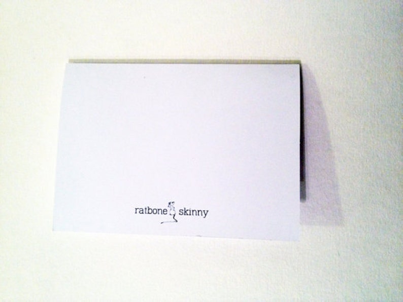 May include: A white card with the text "ratbone skinny" printed in black ink.