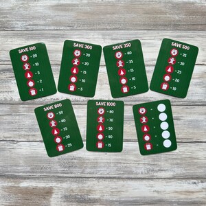May include: Seven green cards with white text and images. Each card has a different amount of money to save, from $100 to $1000. The cards show a gingerbread man, a Christmas tree, a bell, and a gift box. Each item has a different point value.