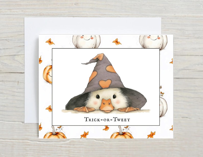 Pu&ograve; includere: Biglietto di auguri di Halloween con un'anatra dei cartoni animati con un cappello da strega con forme di cuore arancioni. Il biglietto ha uno sfondo bianco con zucche e foglie. Il testo "Trick-or-Tweet" &egrave; sotto l'anatra.