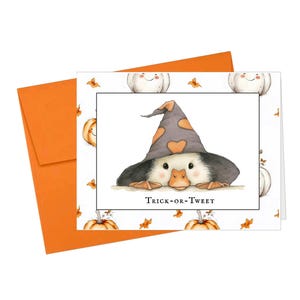 Pu&ograve; includere: Biglietto di auguri di Halloween con un'anatra che indossa un cappello da strega con dettagli a forma di cuore arancione. Il biglietto ha uno sfondo bianco con zucche e foglie autunnali. Il testo "Trick-or-Tweet" &egrave; sotto l'anatra.
