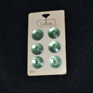 May include: A card of six green plastic buttons with two holes each. The card is labeled "La Mode Buttons" and "39c".