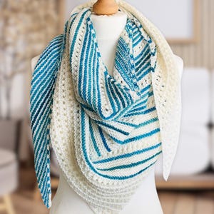 Peut inclure: Un châle en tricot rayé blanc et bleu avec un motif ajouré. Le châle est drapé sur un mannequin blanc.