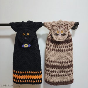 May include: Two crocheted dish towels with cat faces. One is black with orange trim and the other is brown with brown and beige stripes. Both have a purple and yellow belt.