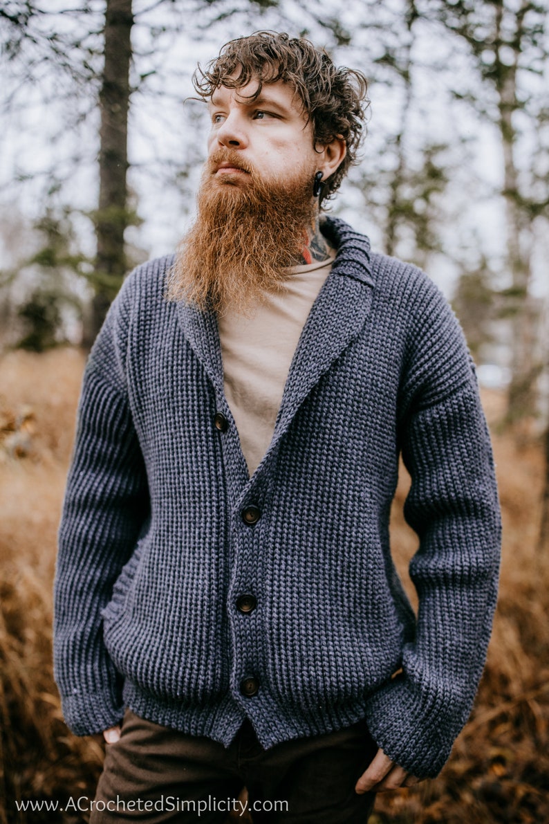 May include: A blue knitted cardigan with a shawl collar and button closure. The cardigan is made with a textured stitch and has a relaxed fit.