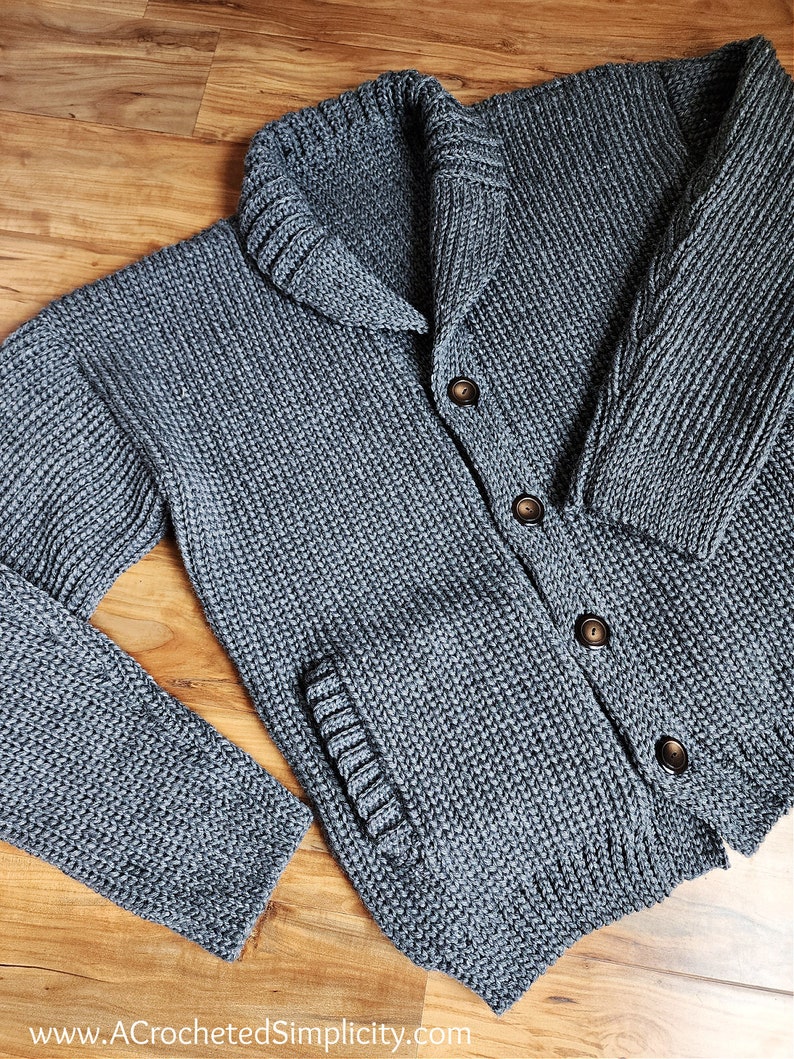 May include: A gray knitted cardigan with a large collar, button closure, and a pocket on the left side.