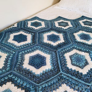 May include: A crocheted blanket with a hexagonal pattern in shades of blue and white.