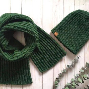 K&ouml;nnte beinhalten: Ein gr&uuml;ner Strick Schal und eine passende Strickm&uuml;tze. Der Schal ist in der H&auml;lfte gefaltet und die M&uuml;tze liegt darauf.
