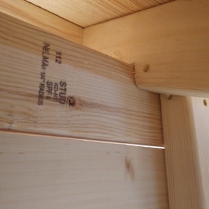 May include: Close-up of a wooden stud with the text "STUD KD-HT 40/4" and "112 NELMA 1 1/4" SPF" printed on it.