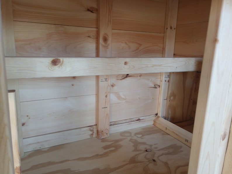 May include: The interior of a wooden cabinet with a shelf. The cabinet is made of unfinished pine wood and has a simple design.