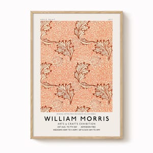 May include: A framed print with a repeating pattern of leaves and fruit in coral, cream, and brown. The print is labelled "Apple Print" and "William Morris Arts & Crafts Exhibition" with dates and times. The print is in a wooden frame.