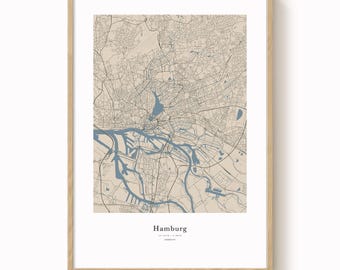 May include: A framed map print of Hamburg, Germany, in a neutral color palette. The map features detailed street and waterway outlines in shades of beige and blue. The city name is printed in a simple font at the bottom.