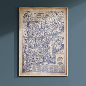 May include: A vintage-style map print titled Clason's Road Map of New England States, featuring dark blue ink on a beige background. The map displays detailed road networks, a map legend, a scale in miles, and an inset map of Eastern Maine.