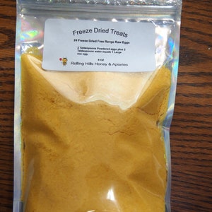 May include: A clear plastic bag filled with yellow freeze-dried egg powder. The label reads "Freeze Dried Treats 24 Freeze Dried Free Range Raw Eggs 2 Tablespoons Powdered eggs plus 2 Tablespoons water equals 1 Large raw egg. 8 OZ Rolling Hills Honey & Apiaries"