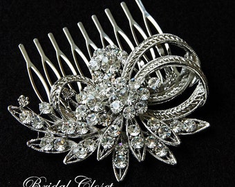 Puede incluir: Peine de pelo plateado con un diseño de lazo de cristal de strass. El peine tiene un patrón floral decorativo con un gran lazo de cristal en el centro.
