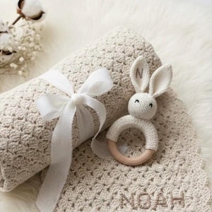 Personalized baby blanket in mushroom beige featuring the name 'NOAH' in a Handcrafted backstitch embroidery style. A cozy, neutral-toned nursery essantial shoen as a high-quality conceptual model.