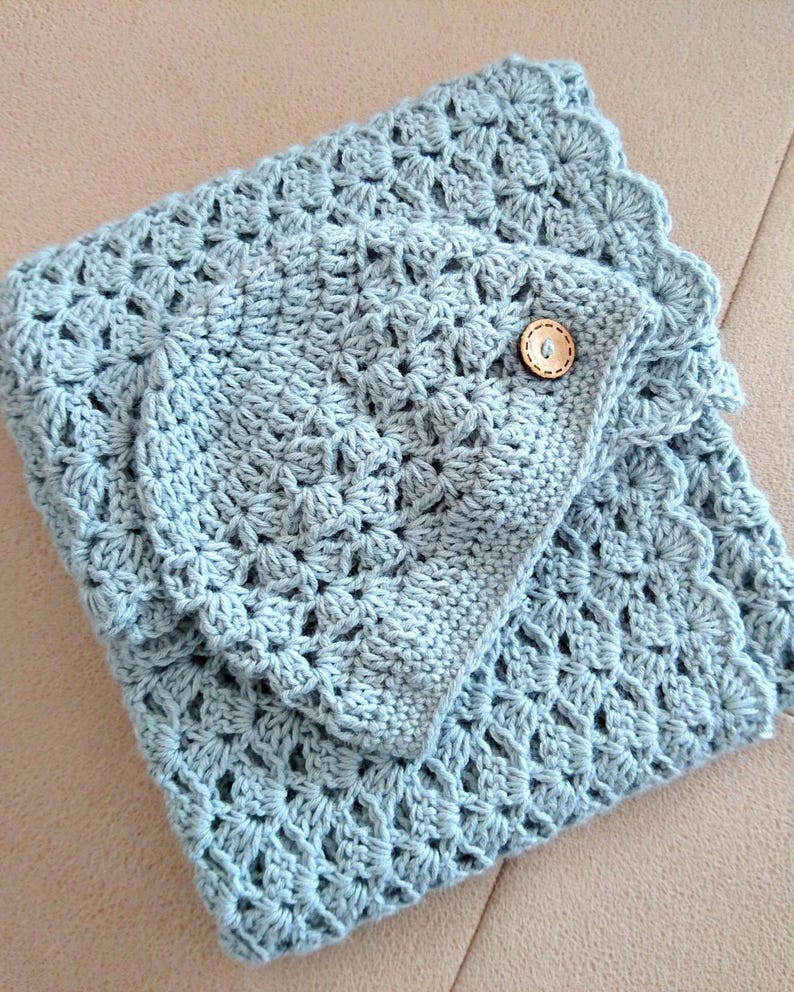 May include: A light blue crocheted blanket and matching pillow cover. The blanket features a detailed openwork pattern and a scalloped edge. The pillow cover is secured with a wooden button. The items are handmade and suitable for home decor.