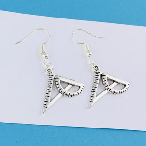 Peut inclure: Une paire de boucles d'oreilles en argent avec un motif de rapporteur et de triangle.