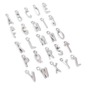 K&ouml;nnte beinhalten: Silberne Alphabet-Buchstaben-Anh&auml;nger, jeder Buchstabe ist einzeln und hat einen Sprungring zum Anbringen an einer Halskette, einem Armband oder einem anderen Schmuckprojekt.