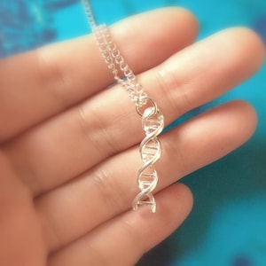 Op de afbeelding: Een zilveren ketting met een DNA-dubbele helix hanger.