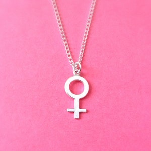 Puede incluir: Un collar de plata con un colgante de s&iacute;mbolo femenino simple.