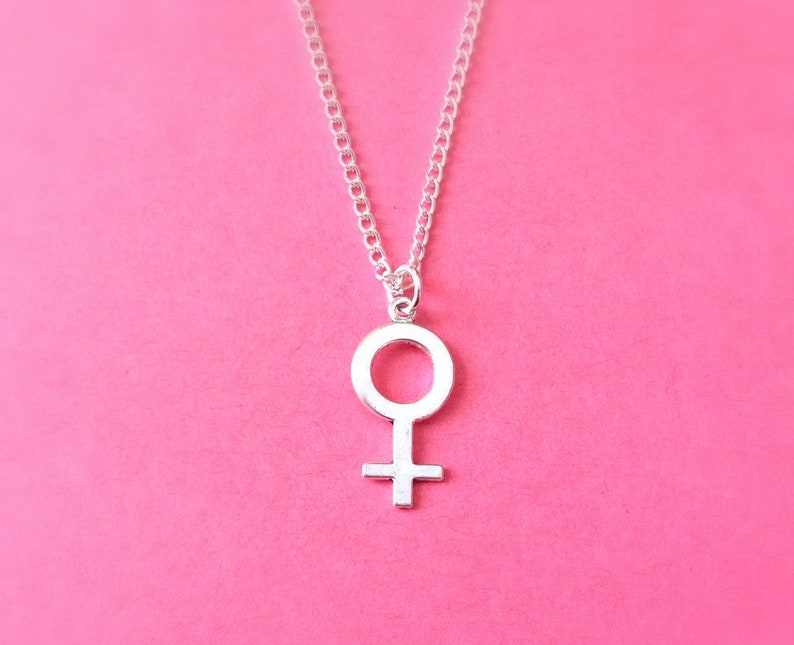 Puede incluir: Un collar de plata con un colgante de s&iacute;mbolo femenino simple.