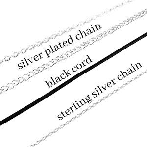 May include: Three necklace options displayed diagonally: a silver plated chain, a smooth black cord, and a sterling silver chain. Each item is labelled with its corresponding name in black text, clearly identifying the material and style of each.