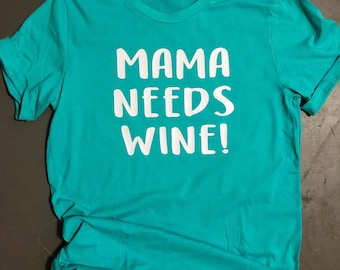 Puede incluir: Una camiseta azul turquesa con el texto "MAMA NEEDS WINE!" impreso en blanco.